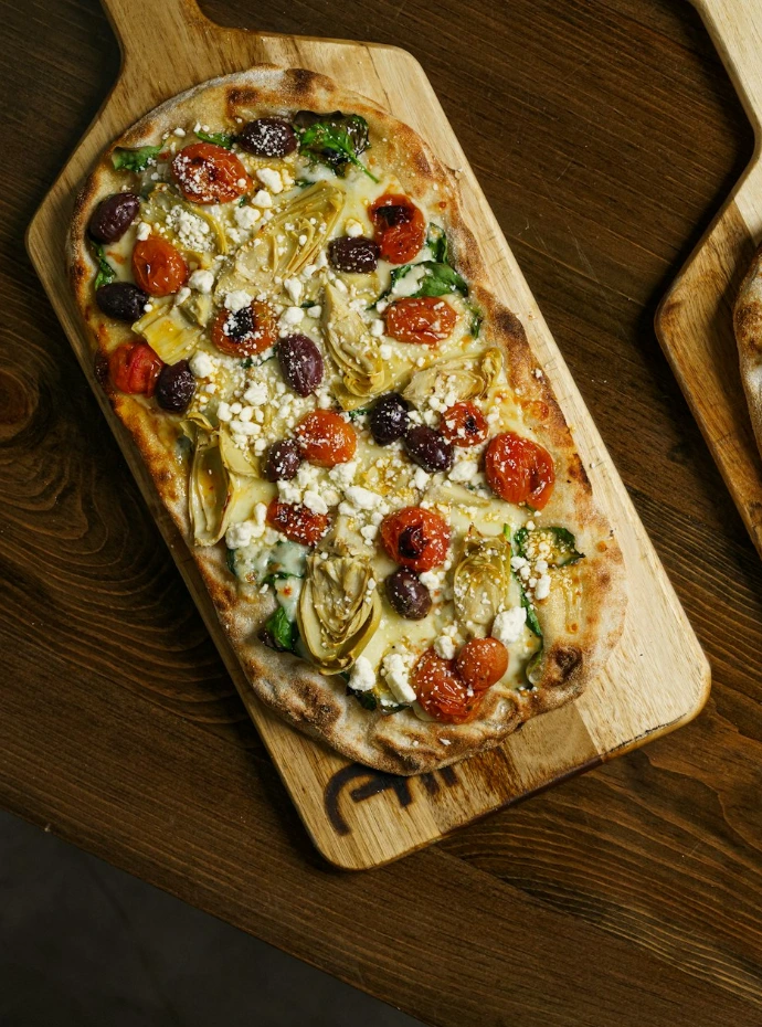 a couple of pizzas sitting on top of a wooden cutting board